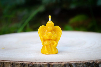 Bičių vaško Angelo žvakute nufotografuota iš arti stovinti ant kelmo