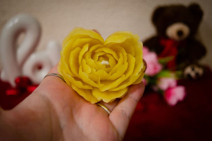 Rankoje laikoma natūralaus bičių vaško rožės formos žvakė.