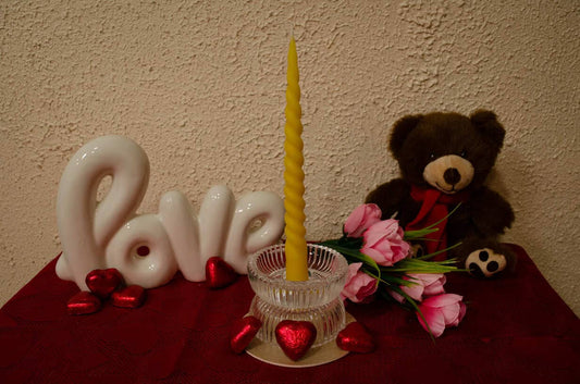 Geltonos bičių vaško suktos vakarienės žvakė romantiškoje kompozicijoje su meškučiu bei dekoratyviniu užrašu „Love“.