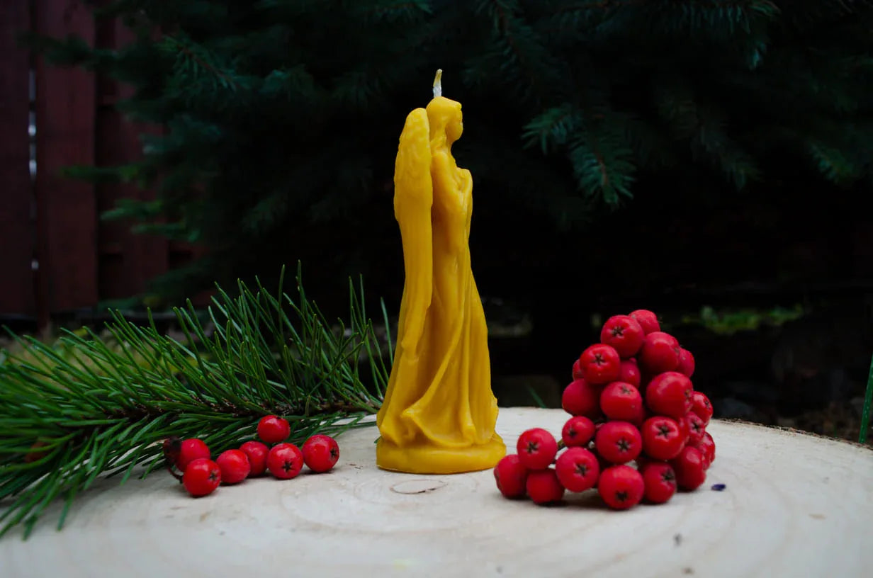 Melora natūralaus bičių vaško žvakė mergelė angelas pastatyta šonu ant kelmo.