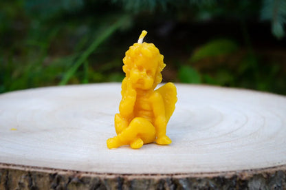 Natūralaus bičių vaško žvakė angeliukas padėtas ant medžio kelmo