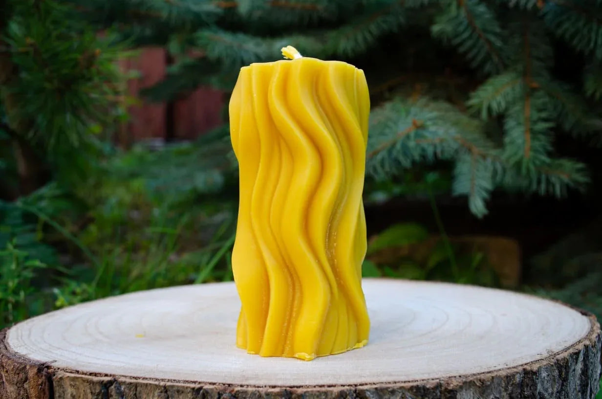 Nuotraukoje matoma bičių vaško žvakė cilindrinės formos išraivyta tarsi bangeles būtų