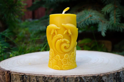 Cilindrinė žvakė su pavaizduotais delfinais pastatyta ant kelmo