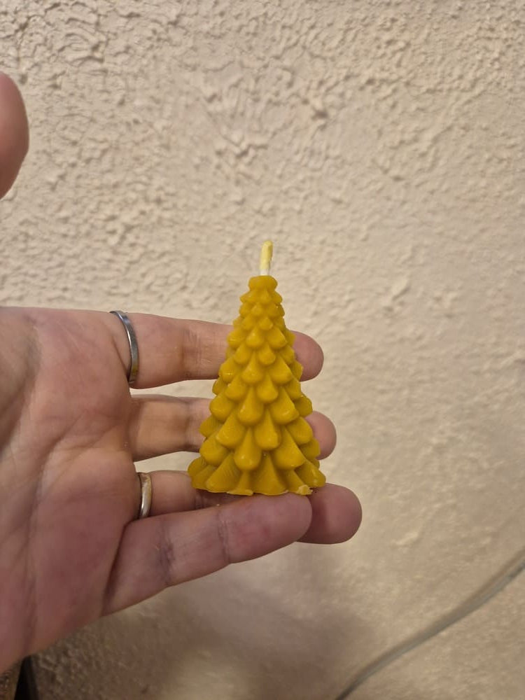 Laikoma rankoje bičių vaško žvakė eglutės formos.