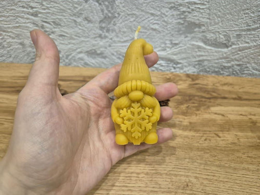 Bičių vaško žvakė elfas su snaige laikoma rankoje rodant gaminio dydį.