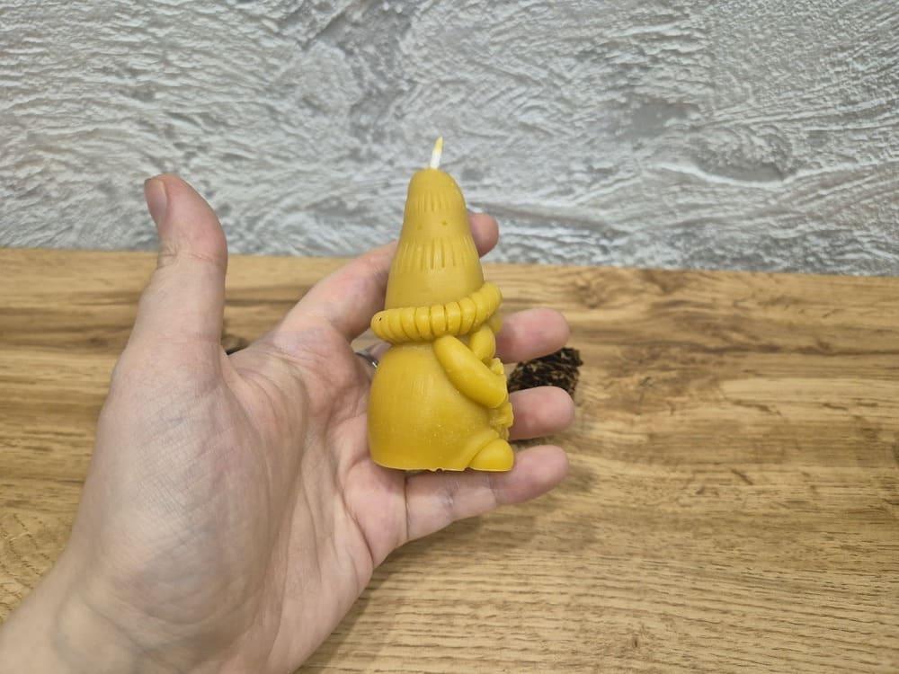 Kalėdinė bičių vaško žvakė elfas laikoma rankoje pasukus į dešinę puse.