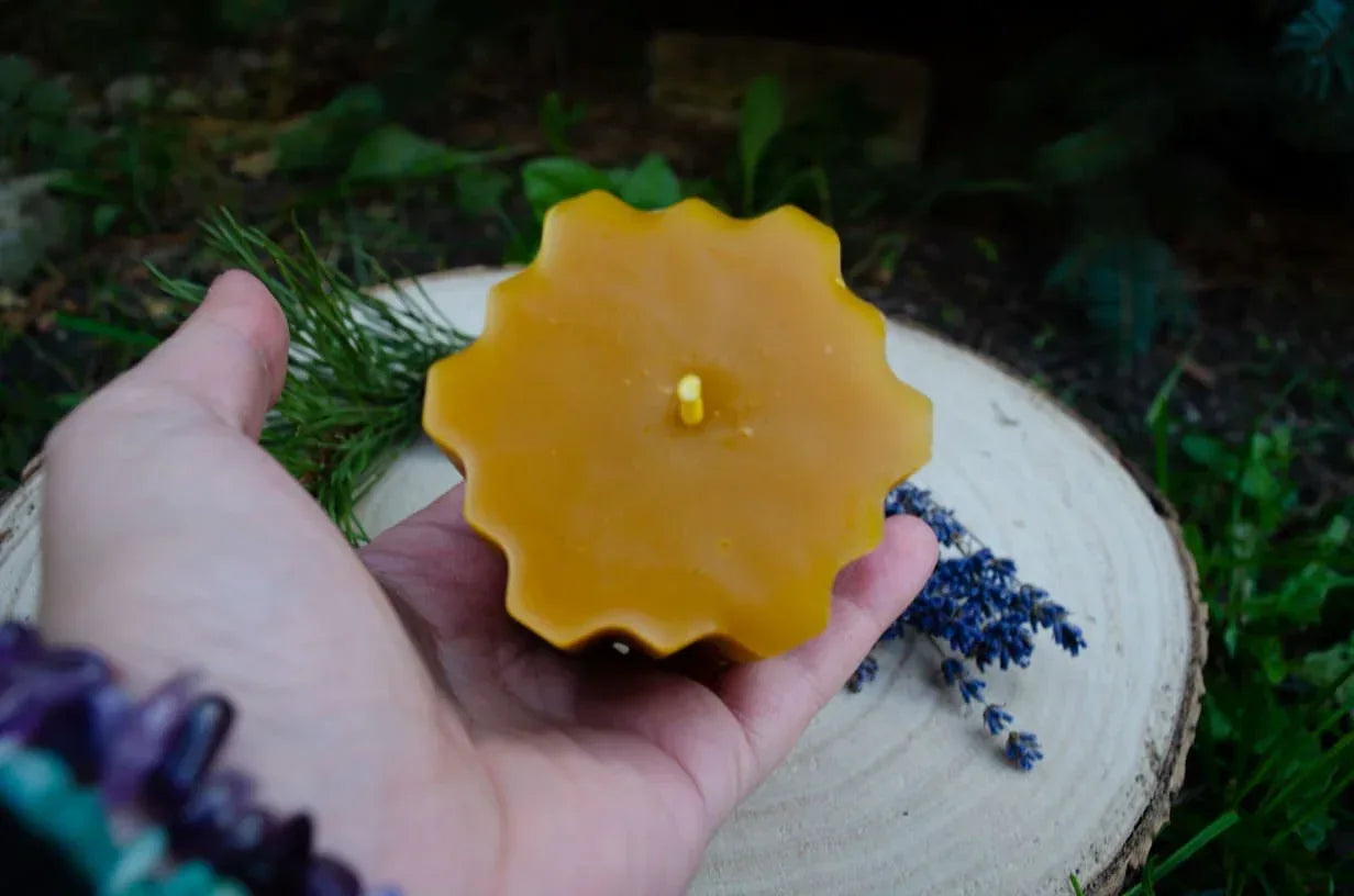 Melora bičių vaško žvakė "Hexas" laikoma rankoje atsukus gaminio viršų į žiūrova.