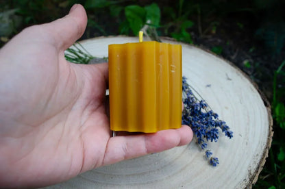 Bičių vaško žvakė "Hexas" laikoma rankoje ir rodant kaip atrodo gaminio šonas.