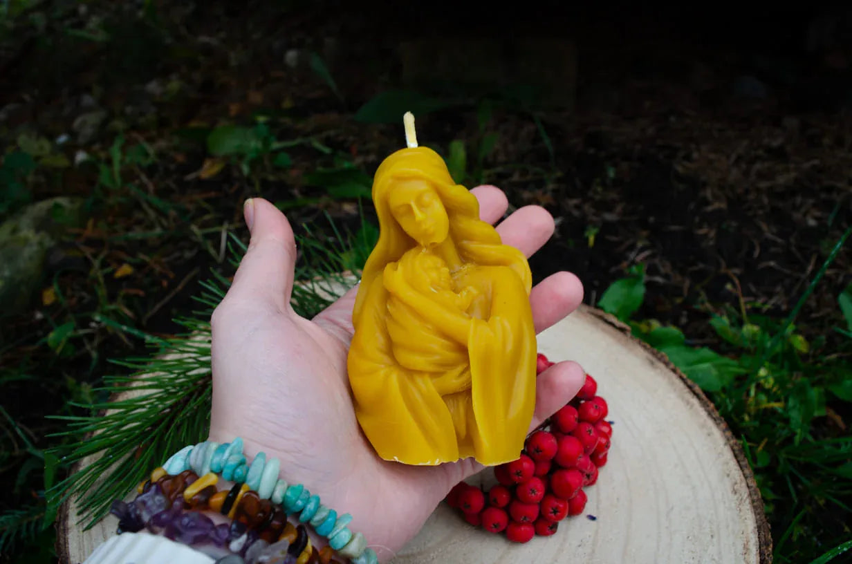 Rankoje laikoma natūralaus bičių vaško žvakė Motinos laikančios kūdikį formos.