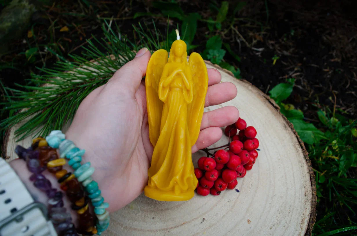 Rankoje laikoma natūralaus bičių vaško žvakė mergelė angelas demonstruojant jos dydį.