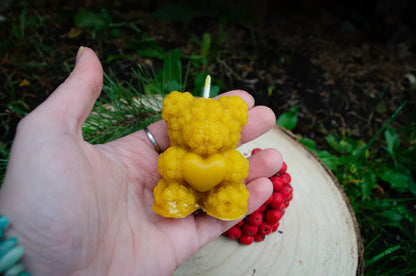 Rankoje laikoma natūralaus bičių vaško žvakė meškiuko laikančio širdelę formos.