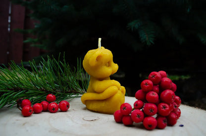 Natūralaus bičių vaško žvakė tigriukas pastatytas ant kelmo šonu.