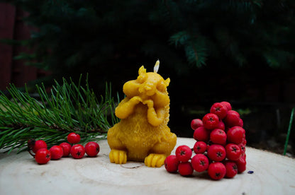 Melora natūralaus bičių vaško žvakė voverės formos pastatyta ant kelmo.